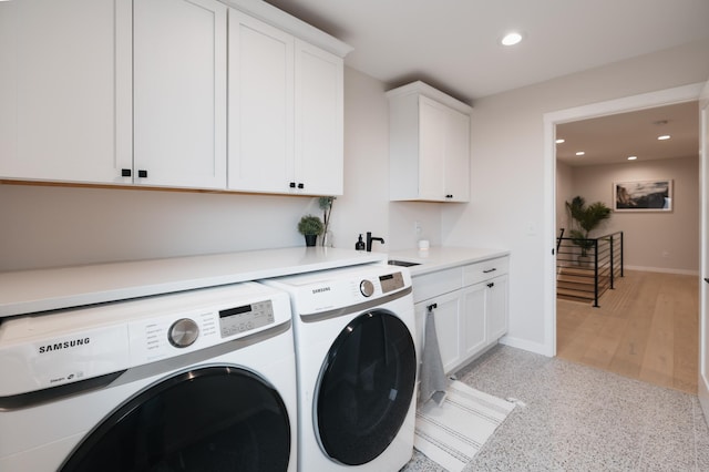 clothes washing area with washer and dryer, a sink, recessed lighting, cabinet space, and baseboards