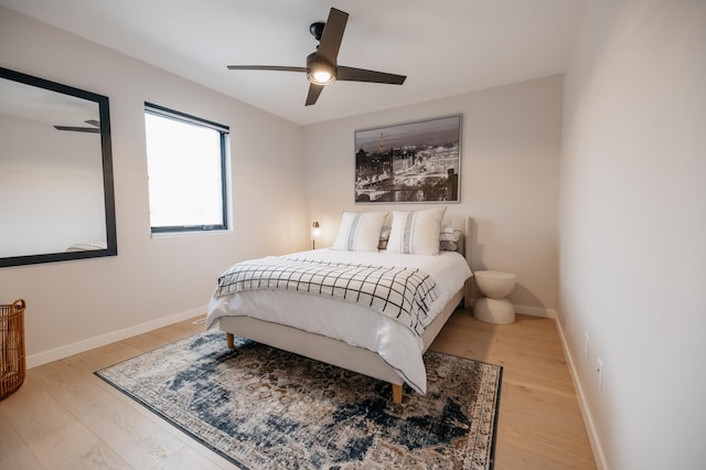 bedroom with a ceiling fan, light wood-style floors, and baseboards