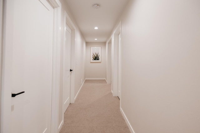 corridor featuring recessed lighting, baseboards, and light carpet