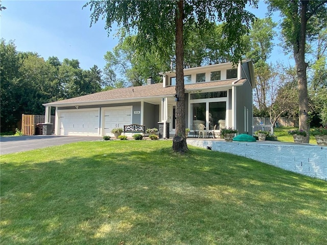 view of front facade featuring a front lawn, an attached garage, fence, and driveway