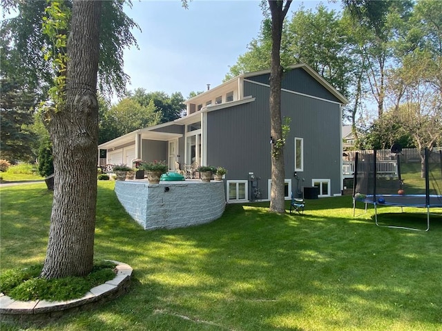 view of side of home featuring a garage, a trampoline, and a yard