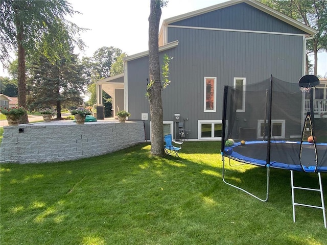 rear view of house featuring a yard and a trampoline