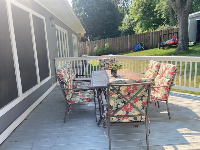 wooden deck with a fenced backyard and outdoor dining space