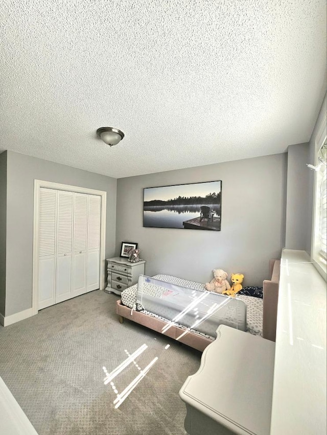 bedroom featuring a closet, carpet flooring, a textured ceiling, and baseboards