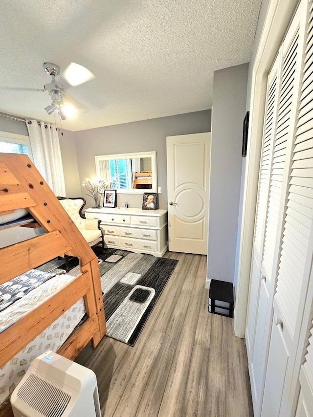 bedroom featuring a closet, light wood-style flooring, a textured ceiling, and ceiling fan