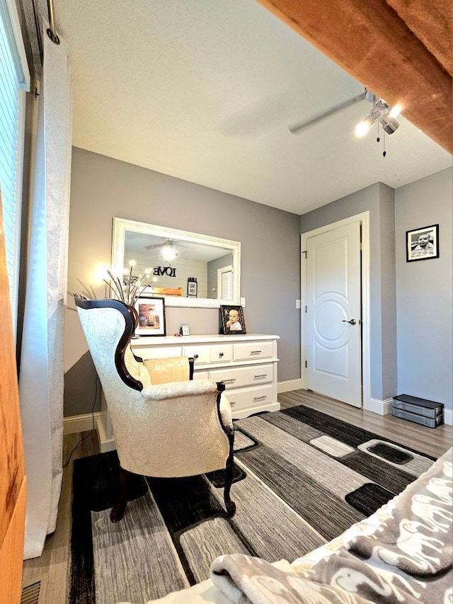 sitting room featuring baseboards, wood finished floors, and a ceiling fan