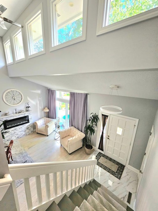 interior space with plenty of natural light, a high ceiling, marble finish floor, and a glass covered fireplace