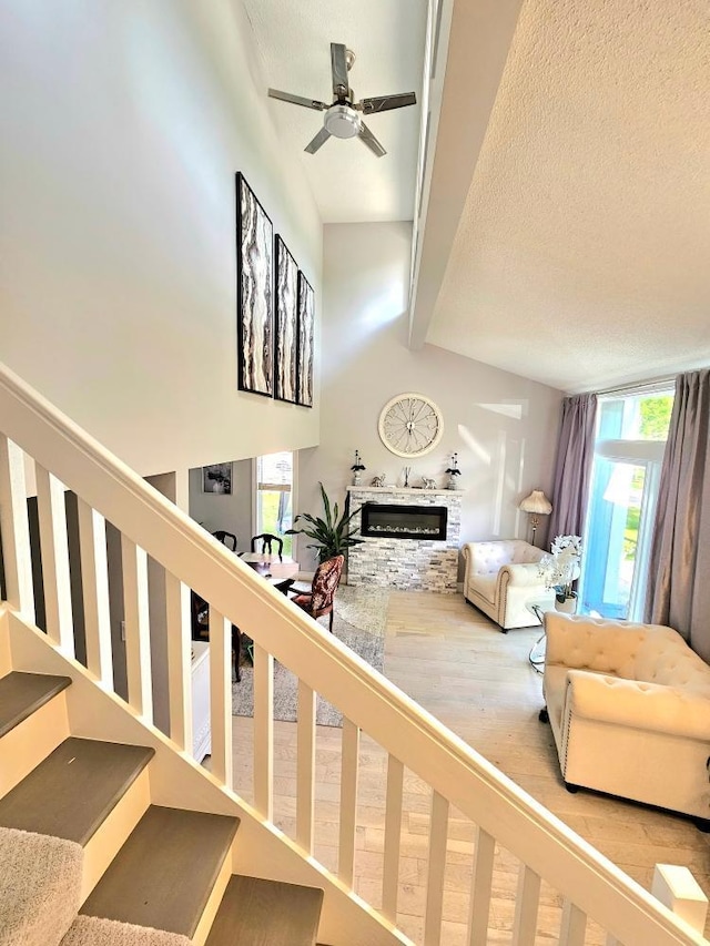 interior space with a wealth of natural light, a stone fireplace, a textured ceiling, and stairs