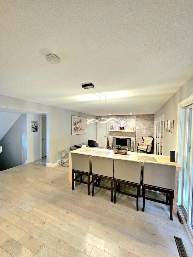 kitchen with light wood finished floors, visible vents, a fireplace, and a textured ceiling