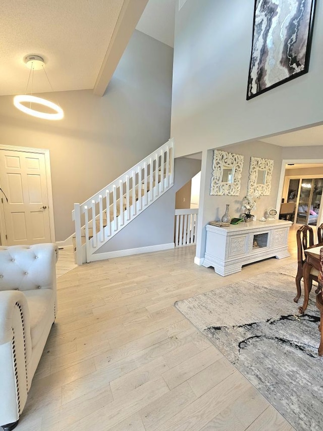 entrance foyer with stairs, a high ceiling, baseboards, and wood finished floors