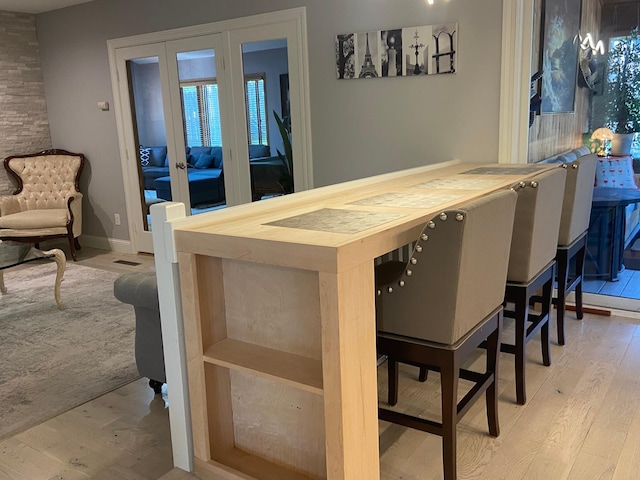 bar with wood finished floors, french doors, visible vents, and baseboards