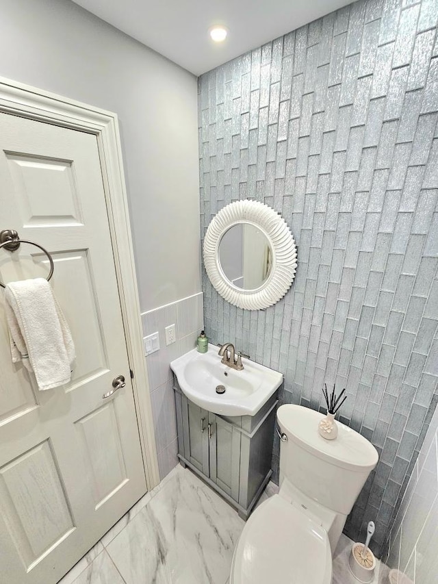 904 155th St, Burnsville, MN 55306 - bathroom featuring tile walls, toilet, marble look tiles, vanity, and recessed lighting
