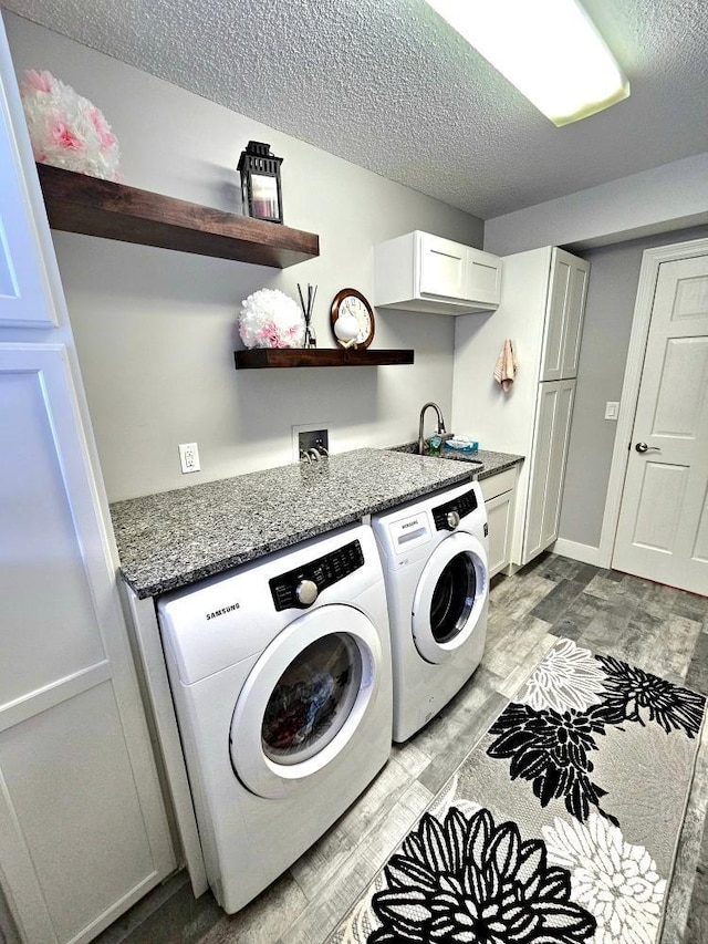 904 155th St, Burnsville, MN 55306 - clothes washing area with washing machine and dryer, light wood-style floors, a textured ceiling, and cabinet space
