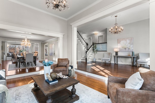 living room featuring an inviting chandelier, wood finished floors, stairs, and ornamental molding