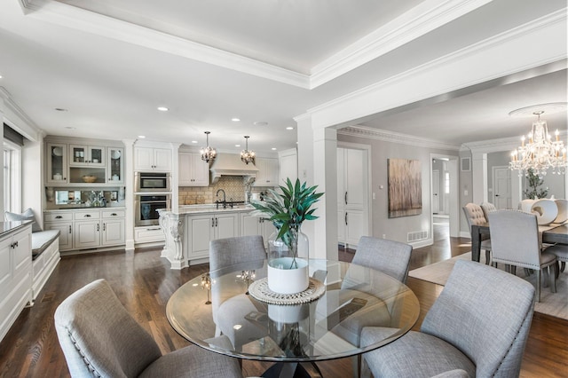 dining area with an inviting chandelier, dark wood finished floors, crown molding, and ornate columns