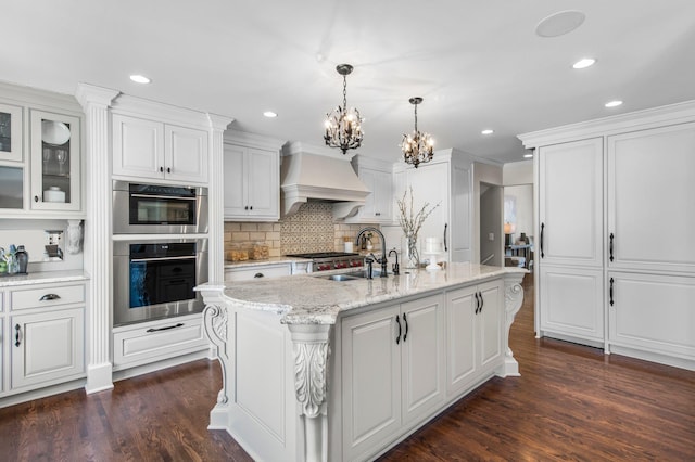 kitchen with a chandelier, custom range hood, dark wood-style floors, white cabinetry, and a sink