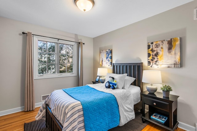 bedroom featuring visible vents, baseboards, and wood finished floors