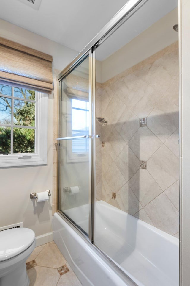 bathroom featuring enclosed tub / shower combo, toilet, a healthy amount of sunlight, and tile patterned flooring