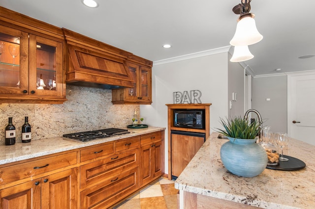 kitchen with ornamental molding, tasteful backsplash, stovetop, brown cabinetry, and black microwave