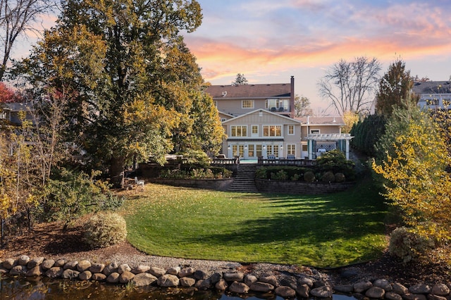 rear view of property featuring a wooden deck, a lawn, and a pergola