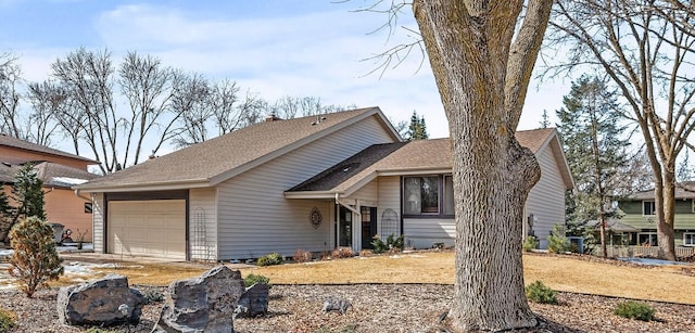 tri-level home with a garage and roof with shingles