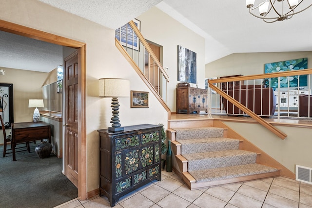 staircase with visible vents, a notable chandelier, a textured ceiling, tile patterned flooring, and vaulted ceiling