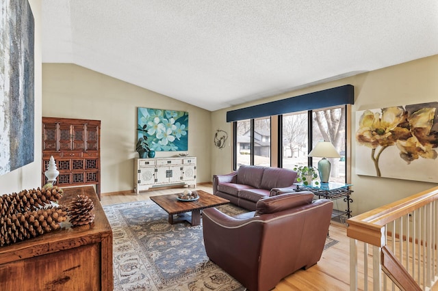 living room featuring a textured ceiling, light wood-type flooring, and vaulted ceiling