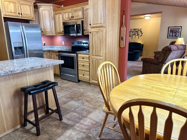 kitchen with light brown cabinets, open floor plan, light countertops, vaulted ceiling, and stainless steel appliances