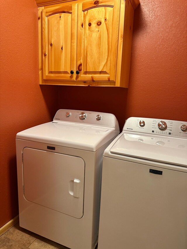 laundry area featuring light tile patterned flooring, cabinet space, baseboards, and washer and clothes dryer