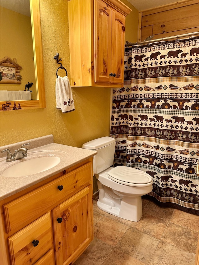 full bath with vanity, a shower with curtain, toilet, and a textured wall