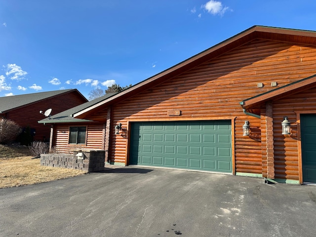 view of side of home with log siding, driveway, and a garage