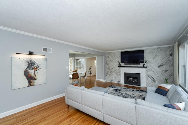 living room featuring light wood finished floors, visible vents, wallpapered walls, baseboards, and a fireplace