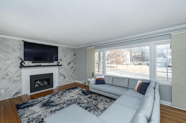 living room with wallpapered walls, crown molding, wood finished floors, and baseboards