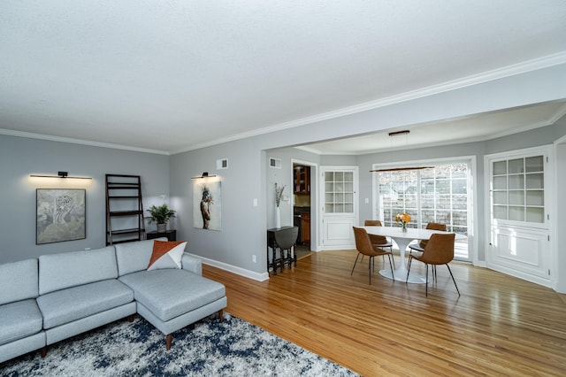 living area featuring visible vents, baseboards, light wood finished floors, and ornamental molding