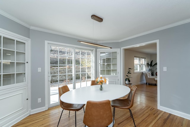 dining area featuring baseboards, light wood-style flooring, and crown molding