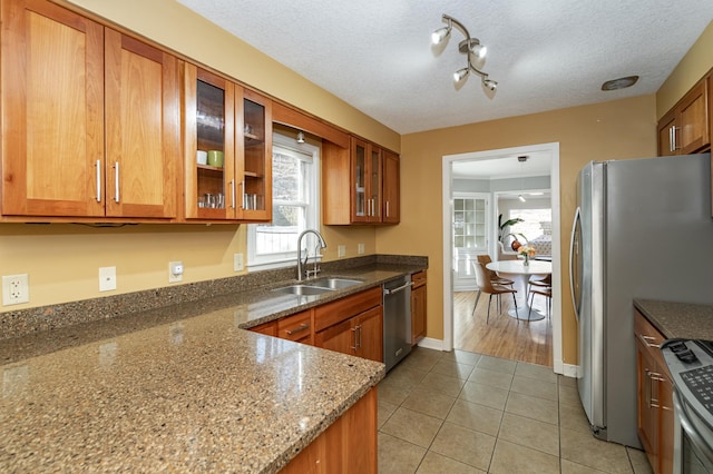 kitchen with a sink, stainless steel appliances, brown cabinets, and light tile patterned floors