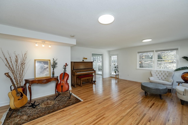 living area featuring light wood-style flooring, baseboards, and a textured ceiling