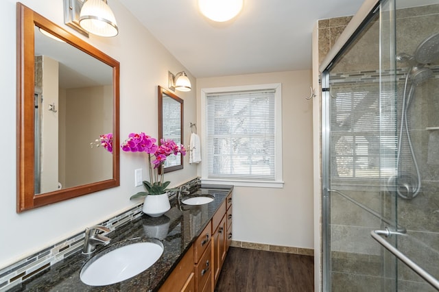 full bath with a sink, a stall shower, and wood finished floors