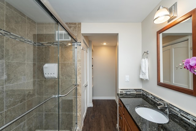 bathroom with vanity, wood finished floors, visible vents, baseboards, and a stall shower