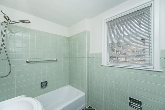 bathroom featuring tile walls, bathing tub / shower combination, and a wainscoted wall