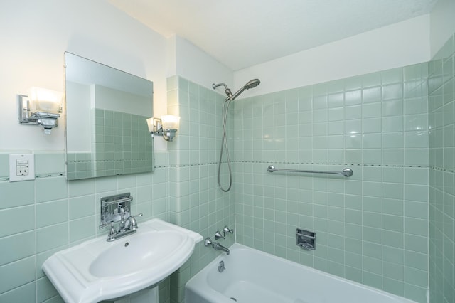 full bathroom with a sink, shower / bath combination, and tile walls