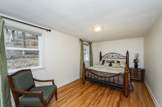 bedroom featuring baseboards, light wood-style floors, and a textured ceiling