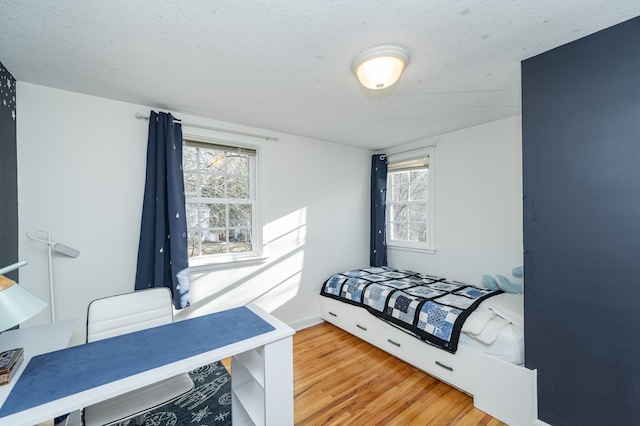 bedroom with wood finished floors, baseboards, and a textured ceiling