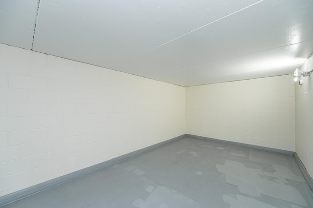 unfurnished room featuring concrete block wall and concrete floors