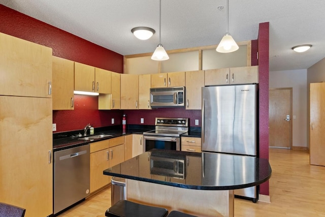 kitchen featuring light brown cabinetry, stainless steel appliances, light wood-type flooring, and a sink