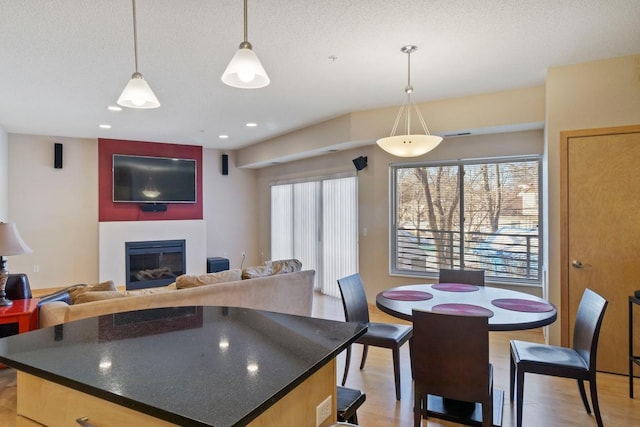 kitchen with a glass covered fireplace, dark countertops, light wood-style flooring, and a textured ceiling