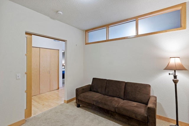 carpeted living room with visible vents, a textured ceiling, and baseboards