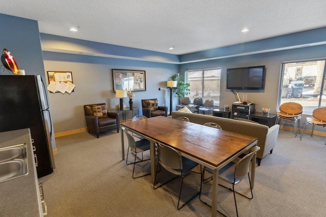 dining space featuring recessed lighting, light colored carpet, a textured ceiling, and baseboards