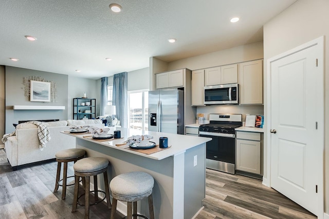 12376 81st St NE, Otsego, MN 55330 - kitchen with appliances with stainless steel finishes, a kitchen island, a kitchen bar, wood finished floors, and open floor plan
