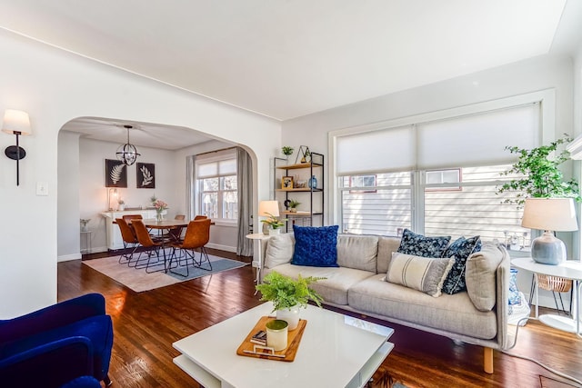 living room with baseboards, arched walkways, and wood finished floors